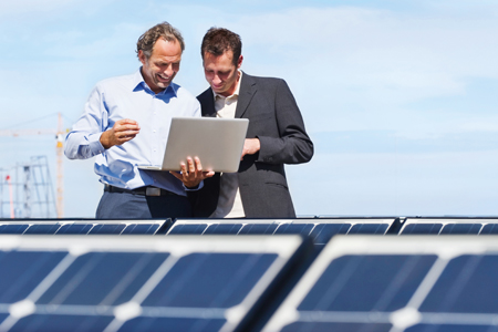 Auf der Baustelle überprüfen zwei Männer im Business-Look etwas an einem Laptop.